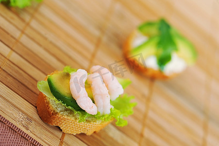 夹着虾、牛油果和生菜的三明治，在竹纸上点缀，小吃