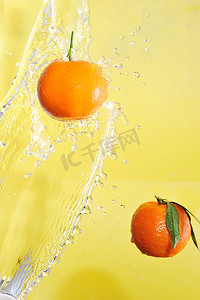 两个橘子和水溅在黄色上，特写