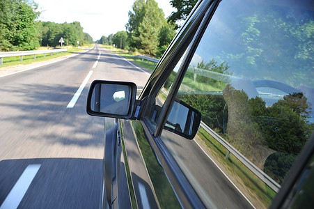 高速路车辆摄影照片_在风景背景下旅行的轿车后视镜