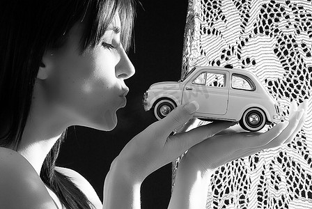漂亮年轻的黑发女郎与一辆意大利风格的菲亚特500汽车接吻