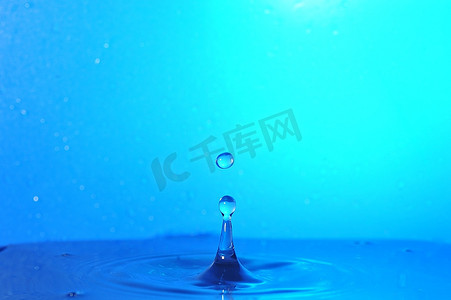 水滴滴落摄影照片_水滴落在水面上并产生涟漪，水滴悬挂在时间中