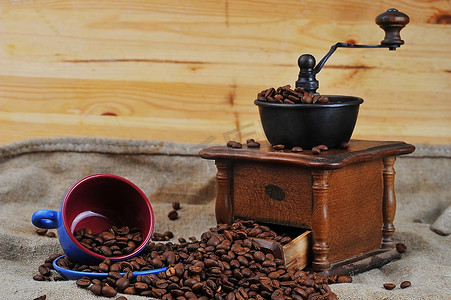 老式手工咖啡研磨机与咖啡豆和杯子