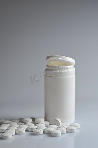 打开的处方瓶和散落在桌子上的白色药片