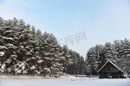 湖畔小屋摄影照片_冰冻湖畔的小屋，紧随其后的是冬季森林