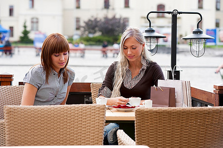 两个美丽而老练的年轻女性朋友在城市咖啡馆喝咖啡