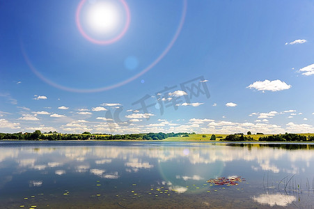 平静的湖水，对岸的树林和蔚蓝的天空。景观