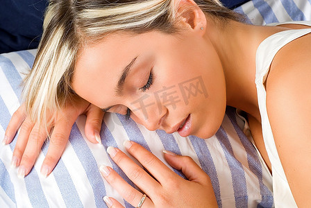 记忆棉头枕摄影照片_一个年轻的金发女子的漂亮特写，头枕在枕头上睡着了
