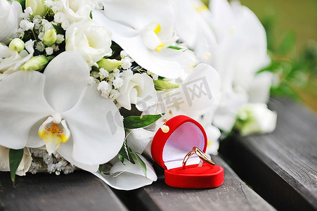 木凳上摆放着一束白兰花和结婚金戒指