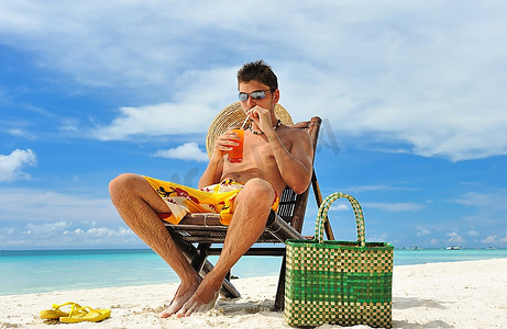男子在一个热带海滩与鸡尾酒