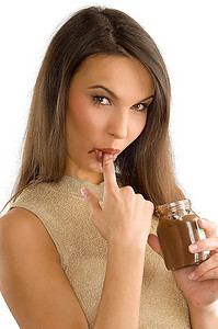 性感的女孩用巧克力奶油吮吸手指