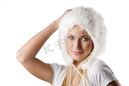 一个年轻美丽的模型的肖像在白色的冬天礼服与一个漂亮的毛皮帽子看在照相机