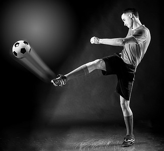 大力神纹摄影照片_足球运动员在黑暗中大力击球