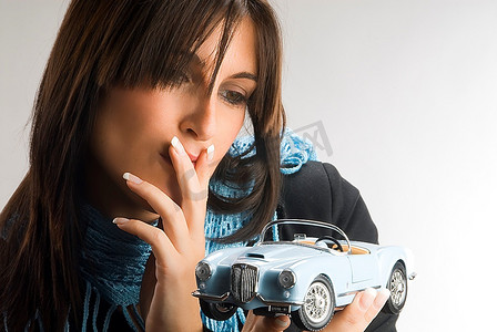 一位年轻优雅的女士饶有兴趣地看着一辆蓝旗亚汽车模型