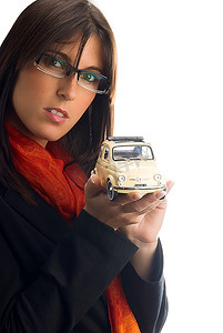 特例摄影照片_戴着眼镜的年轻黑发女郎展示了一辆菲亚特500车型，一辆老式的意大利风格汽车