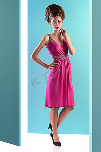 摆在绿松石背景的一个优雅的少妇时尚射击穿粉红色晚礼服和时尚向上做