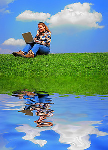 拿着笔记本的女孩坐在草地上映照着天空