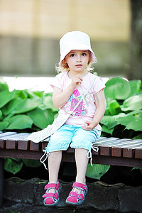 小女孩坐在公园长椅上