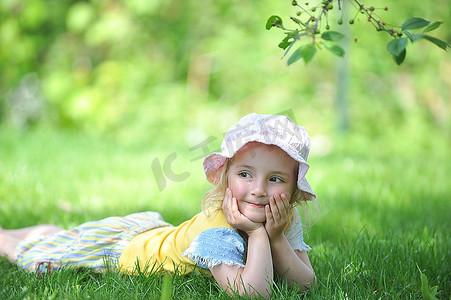 美丽五一摄影照片_帽子的顽皮的小女孩在草地上。五一