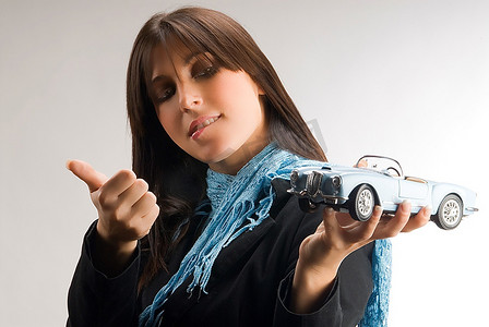 一位年轻优雅的女士饶有兴趣地看着一辆蓝旗亚汽车模型