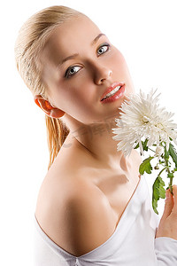 年轻可爱的金发女孩的美丽肖像，白色上衣，脸部附近有一些鲜花