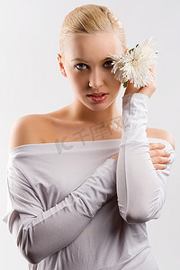花上衣摄影照片_年轻可爱的金发女孩的美丽肖像，白色上衣，脸部附近有一些鲜花