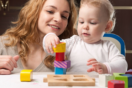 brincando摄影照片_Mother and baby daughter building tower