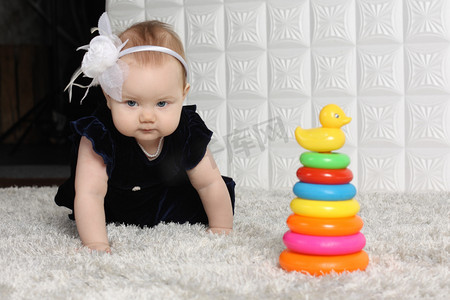 裙子的小可爱宝宝爬行玩具之间的灰色软地毯上.