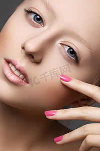 make摄影照片_Beautiful young model with natural make-up and bright pink manicure. Wellness. Close-up beauty portrait of lovely european woman with clean healthy skin, pale lips, vibrance nail polish. Spa look