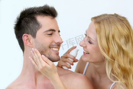 涂抹防晒霜在她男朋友的脸颊上的女人
