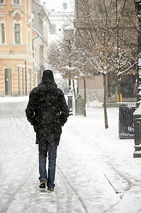 走在被雪封住的城市小巷里的男人.