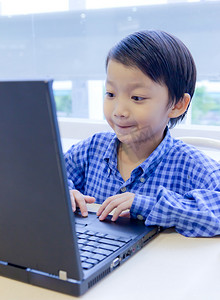 辐射量摄影照片_用便携式电脑和笔记本电脑的亚洲孩子