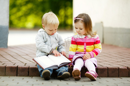 一本书照片摄影照片_可爱的男孩和女孩读一本书