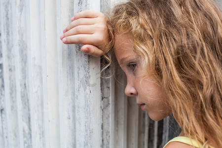 悲伤小女孩在老墙上的背景