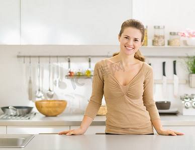 白色的现代厨房摄影照片_现代厨房里笑着的年轻家庭主妇的画像