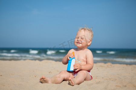 婴儿护肤摄影照片_可爱女孩在海滩应用防晒霜