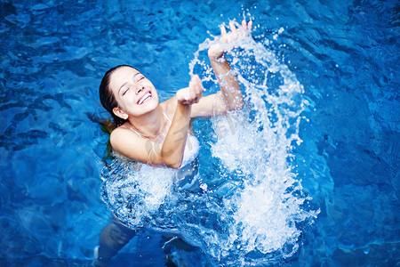 水谭摄影照片_年轻漂亮的女人泼在游泳池中的水