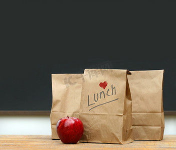 自助水果摄影照片_午餐袋与学校桌子上的苹果