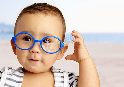 婴儿在行动摄影照片_小男孩戴着蓝眼镜的肖像