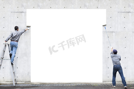 一套展架海报摄影照片_两名工人正在画在墙上的空白区域