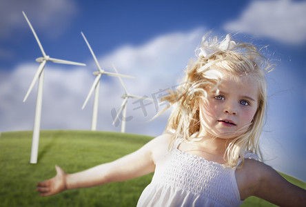 年轻美丽的女孩在风力涡轮场玩