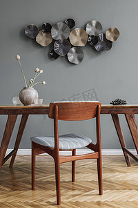 现代时尚的餐厅内部,有迷人的木制餐桌,雅致的椅子和设计装饰. 模板。 家居装饰。 灰色背景墙。 室内设计的最低限度概念.