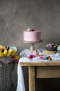 彩绘花摄影照片_复活节餐桌装饰, 美味的自制蛋糕与春天的花朵和彩绘鸡蛋在假日餐桌上。篮子新鲜安置接近复活节桌
