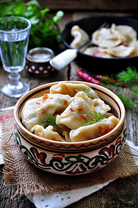 plate摄影照片_Dumplings with potatoes and mushrooms with fried onions in a traditional ceramic plate on a wooden table. Ukrainian traditional cuisine. rustic style. selective focus