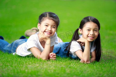 躺在绿草地上的两个小的亚洲女孩
