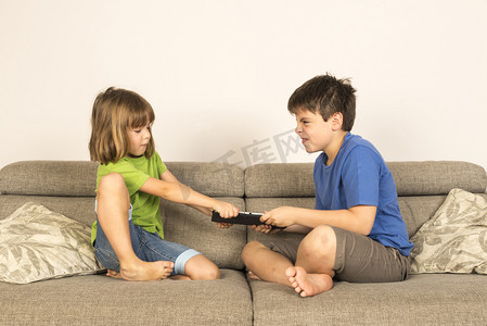 孩子们争论玩弄数字平板电脑在沙发上.