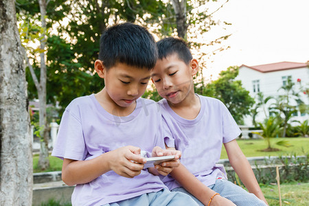 科技生活互联网摄影照片_双胞胎男孩玩手机.