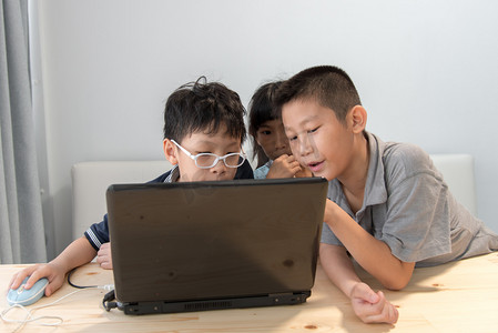 便携式摄影照片_三个亚洲的孩子在家里使用便携式计算机