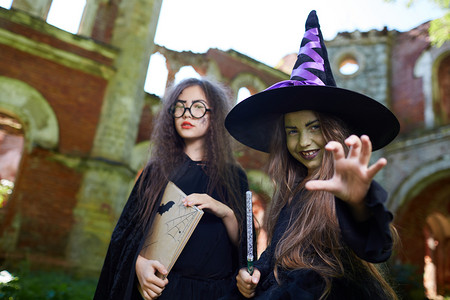 腰起两个十几岁的女巫看着相机，而在万圣节在怪异的城堡摆姿势，复制空间
