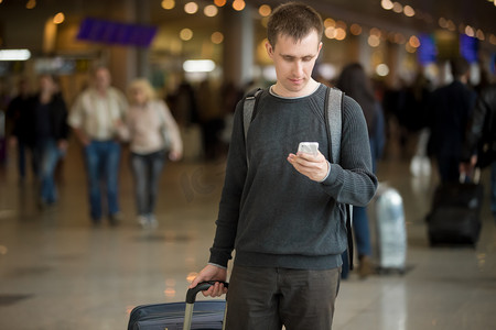 旅游征集摄影照片_年轻的旅行者在机场中使用手机 