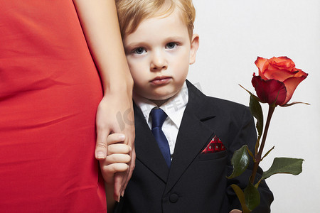 在与母亲的衣服的孩子。花。红色的连衣裙。家庭。时尚的小男孩。红玫瑰。牵着的手